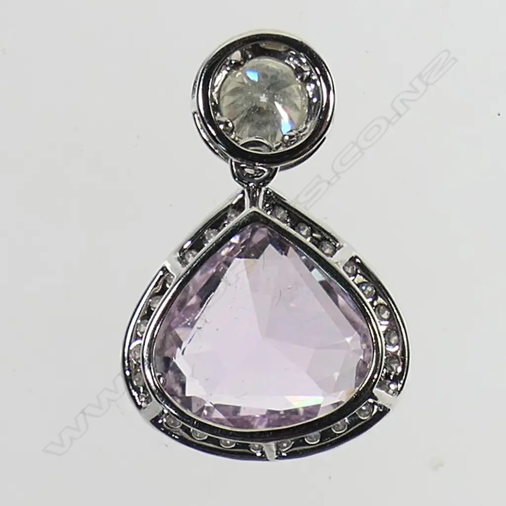 A 14ct white gold kunzite and diamond halo drop pendant - a 4.43ct trillion cut light pink-purple kunzite (minor eye visible inclusions), claw set, surmounted by a 0.36ct round brilliant cut diamond. Embellishing the design in individual halos are forty-five round brilliant cut diamonds (Colour J-K, Clarity SI-SI2), micro claw set. TDW. 0.60ct. Image 1++