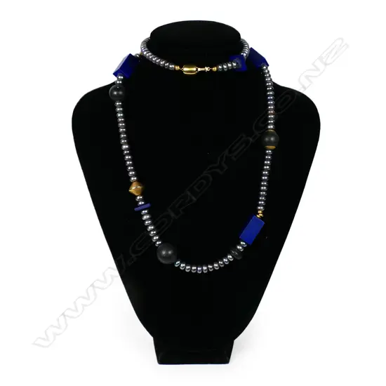 A modern designer fresh water pearl lapis lazuli onyx and gold necklace - the 99 fresh water pearls of grey to purple tone and 6.4 to 6.9mm diameter highlighted with six round onyx beads, five lapis beads and various gold plated beads, with 14ct yellow gold clasp. L.730mm. Valuation available.