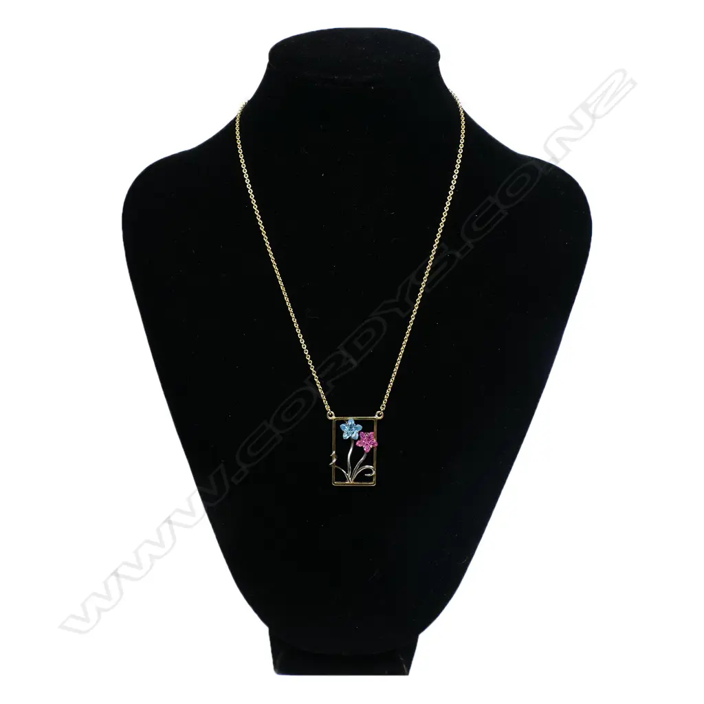 An 18ct gold modern designer pendant necklace - the rectangular open pendant with white gold restrained floral design set with a fantasy cut blue tourmaline and a pink sapphire as the flower heads. suspended on an 18ct gold chain. 11.34gms. Image 1++