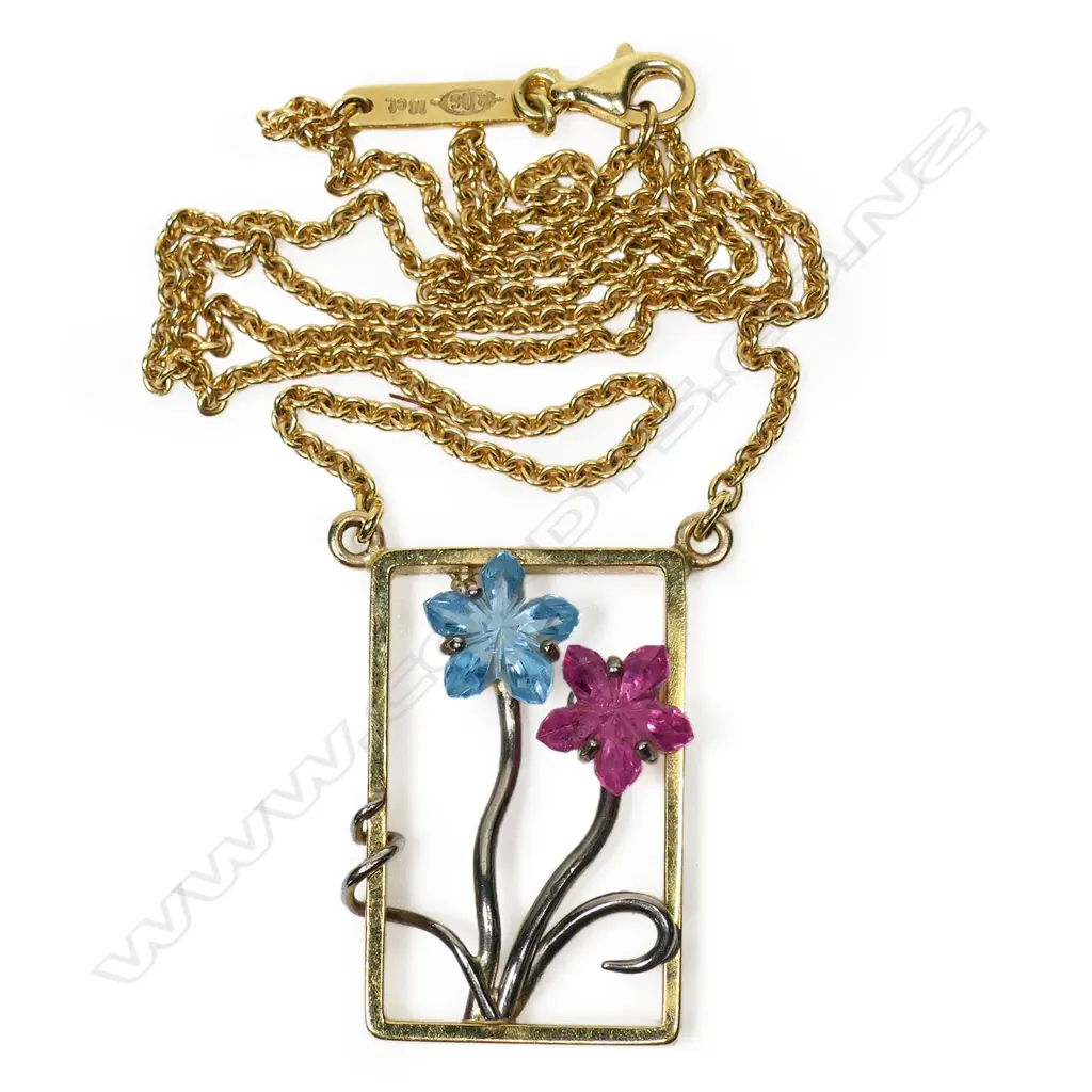 An 18ct gold modern designer pendant necklace - the rectangular open pendant with white gold restrained floral design set with a fantasy cut blue tourmaline and a pink sapphire as the flower heads. suspended on an 18ct gold chain. 11.34gms. Image 1++