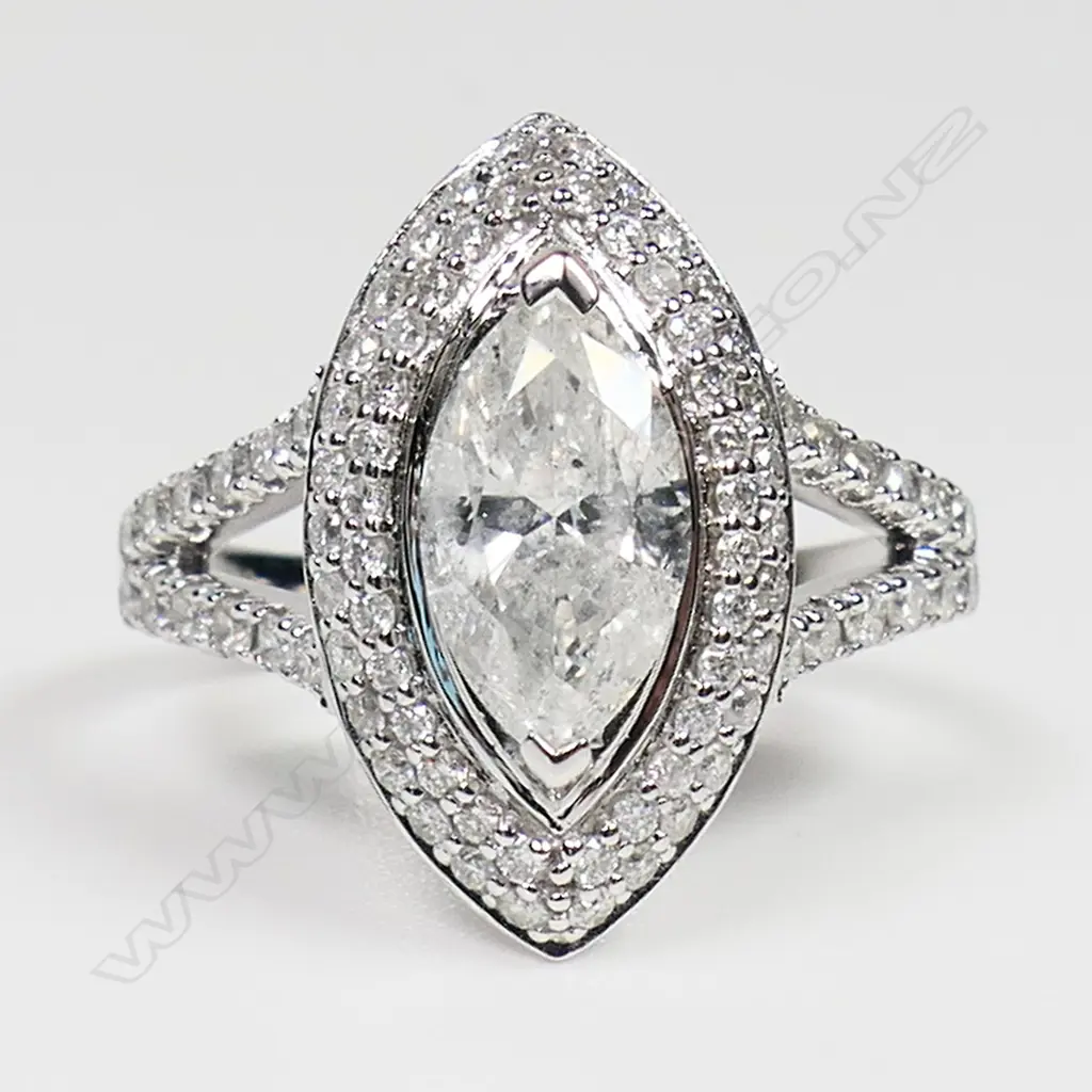 A 14ct white gold diamond double halo ring - a 1.06ct marquise cut diamond (Colour G-H, Clarity SI1-SI2), claw set and surrounded by a double halo of round brilliant cut diamonds with further diamonds set to the split shoulders (Colour H-H, Clarity SI1-SI2), micro bead set. TDW. 1.72ct. Ring size M. Image 1++