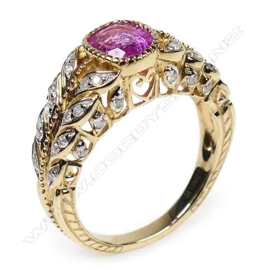 A 14ct gold pink sapphire and diamond dress ring - a 1.03ct oval facet cut deep purplish-pink sapphire (minor eye visible inclusions), bezel set, decorating the leaf inspired band and mount are forty round brilliant cut diamonds (Colour J-K, Clarity SI2-I2), micro claw set. TDW. 0.21ct. Ring size L.