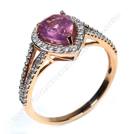 A 14ct rose gold pink sapphire and diamond halo ring - a 1.54ct pear cut orangish-pink sapphire (minor eye visible inclusions), claw set and surrounded by a halo of round brilliant cut diamonds (Colour J-K, Clarity SI2-I2), bead set in white gold with further diamonds to the split shoulders. TDW. 0.27ct. Ring size N.