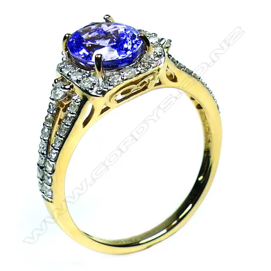 A 14ct gold tanzanite and diamond halo ring - a 1.72ct oval cut purplish-blue tanzanite (minor eye visible inclusions), claw set and surrounded by a halo of round brilliant cut diamonds (Colour J-K, Clarity SI2-I2), bead set, with further diamonds to the split shoulders. TDW. 0.33ct. Ring size M.