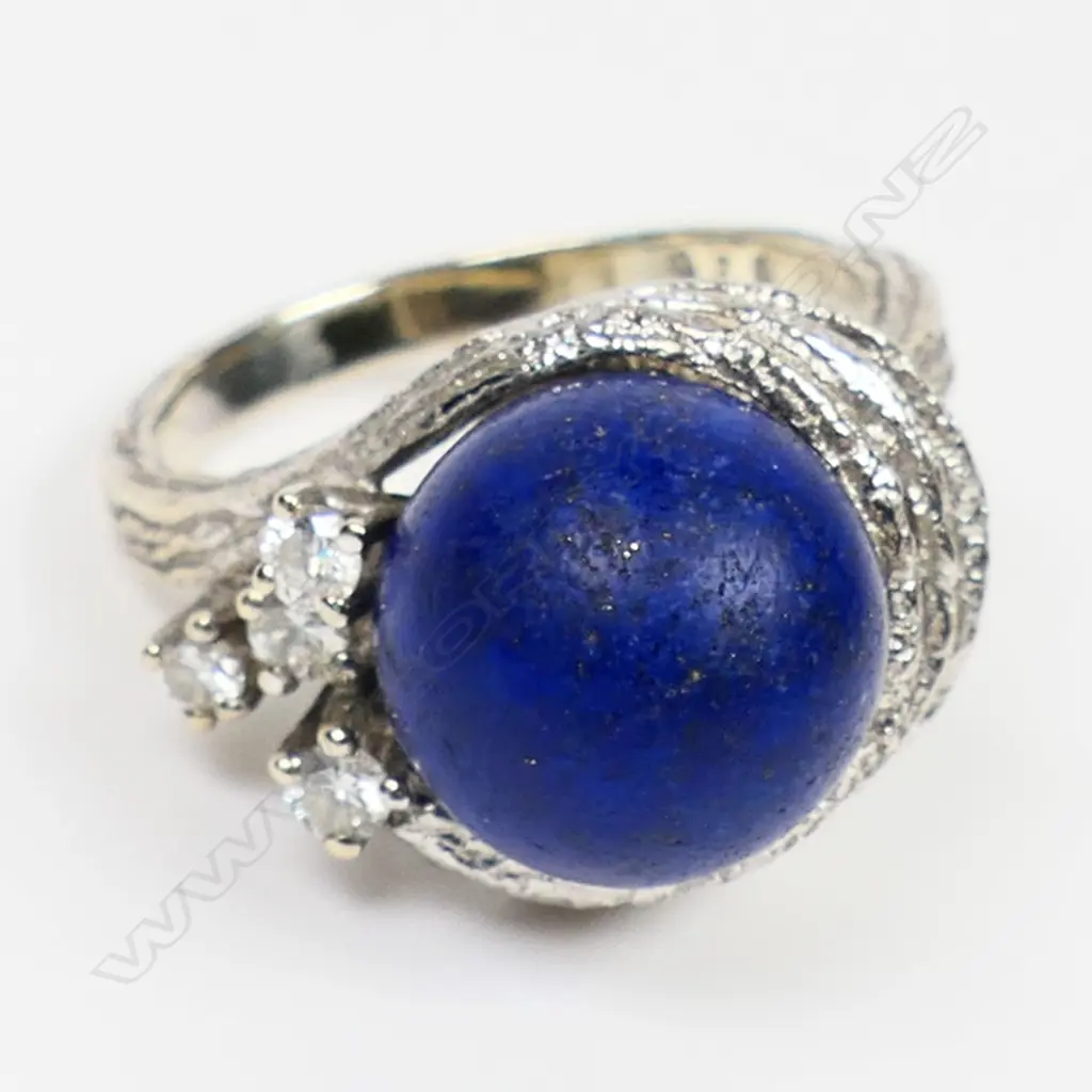 A 14ct white gold lapis lazuli and diamond set designer ring - the round cut lapis lazuli of 11mm diameter in a textured multi ring mount highlighted with four round brilliant cut diamonds. 7.1gms. Valuation available. Image 1++