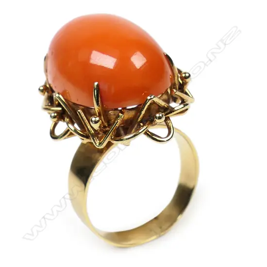 A vintage 14ct yellow gold and coral ring - the large oval orange / red coral cabochon claw set in collet with ornate wire undersetting. 11gms. Valuation available.