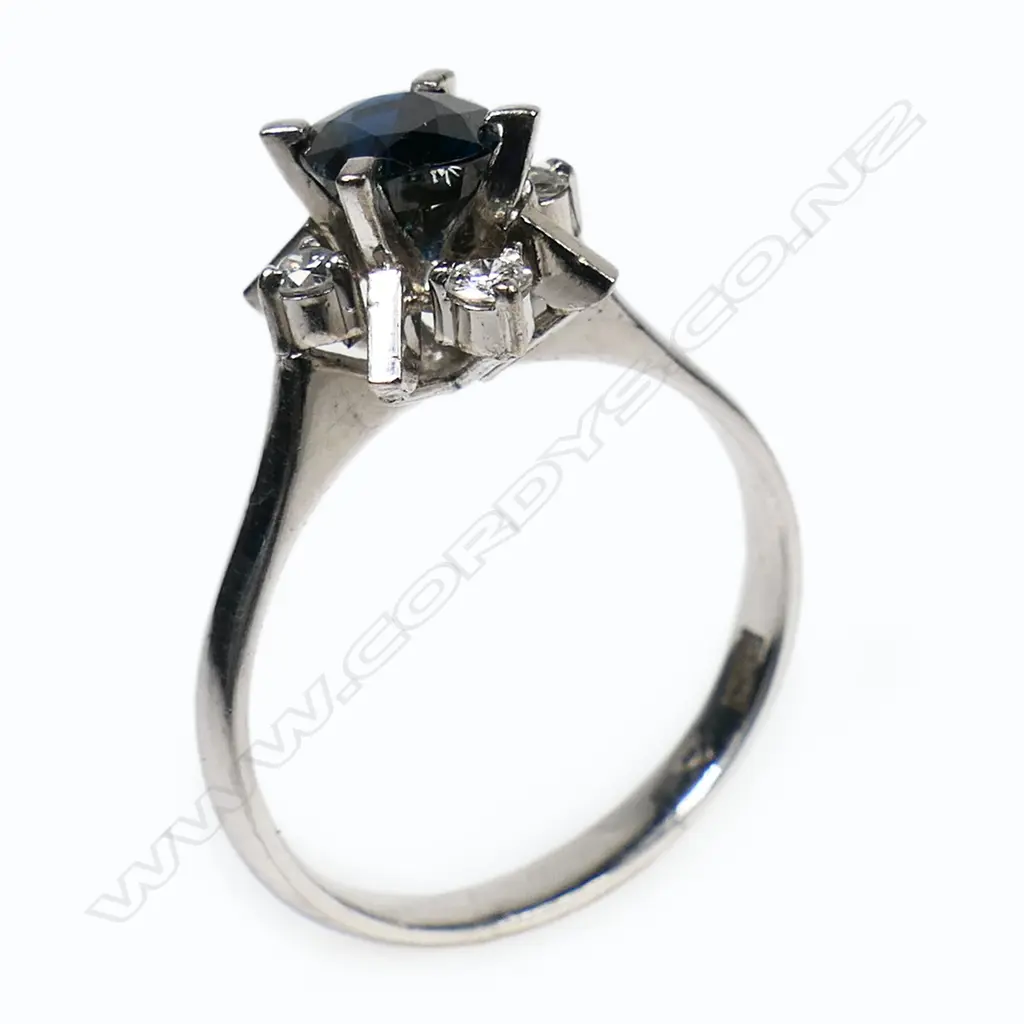 A 14ct white gold sapphire and diamond antique style ring - a 0.98ct oval cut deep royal blue sapphire (slight-moderate inclusions), claw set with four round brilliant cut diamonds (Colour F-G, Clarity VS1) claw set. TDW.0.10ct. Ring size N. Image 1++