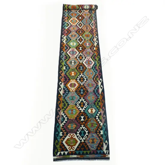 A Turkish hand-knotted kilim runner, decorated with multi-coloured diamond form medallions with geometric border guards.  5000 x 820mm.