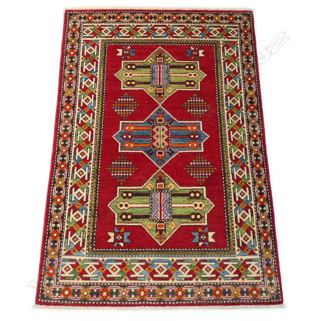 A good hand knotted Kazak rug, the field decorated with three geometric medallions with internal decoration, on a red ground, the border guards with multi-coloured geometric motifs. 1500 x 1000mm. Image 1++