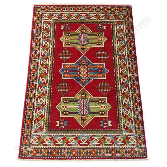 A good hand knotted Kazak rug, the field decorated with three geometric medallions with internal decoration, on a red ground, the border guards with multi-coloured geometric motifs. 1500 x 1000mm.