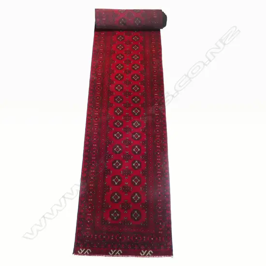 A hand-knotted Turkman runner, the field decorated with numerous guls, multiple border guards, in traditional reds and black. 5900 x 800mm.