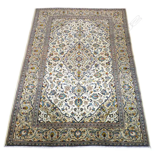 A quality hand-knotted Kashan carpet, the field decorated with a central medallion surrounded by flowing tendrils and conforming small medallions on an ivory ground, deep cream quadrants, multiple border guards.