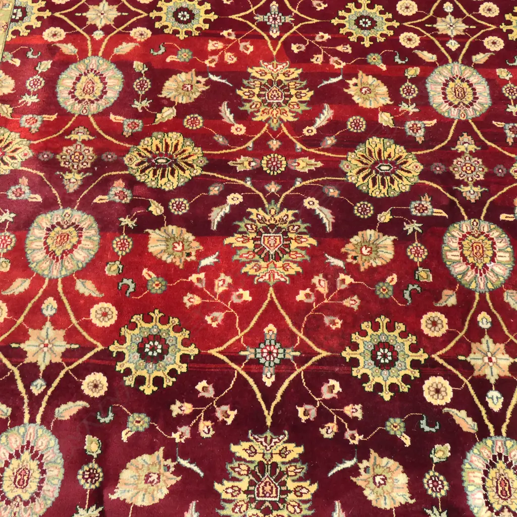 A large Indo-Persian hand-knotted wool on cotton rug, the maroon field decorated with floral medallions surrounded by flowering vines, multiple border guards with geometric shapes. (Retail $7,000 in 2014). 2400 x 3130mm. Image 1++