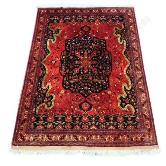 A fine hand-knotted wool rug, the field decorated with a large central medallion surrounded by trailing flowering vines, each end with castellated style decoration, multiple border guards. 2050 x 4000mm.