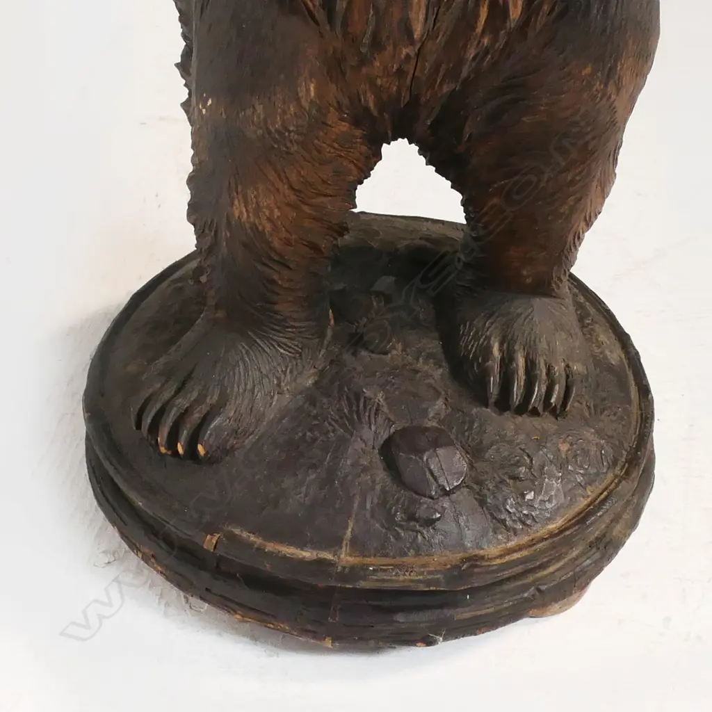A late 19thC Black Forest carved large floor standing bear with basket - he stands holding aloft a pierced and carved branch form basket. His open mouth with carved and white painted teeth, glass set eyes. On circular domed base with further carved naturalistic detail. H.945mm. Image 1++