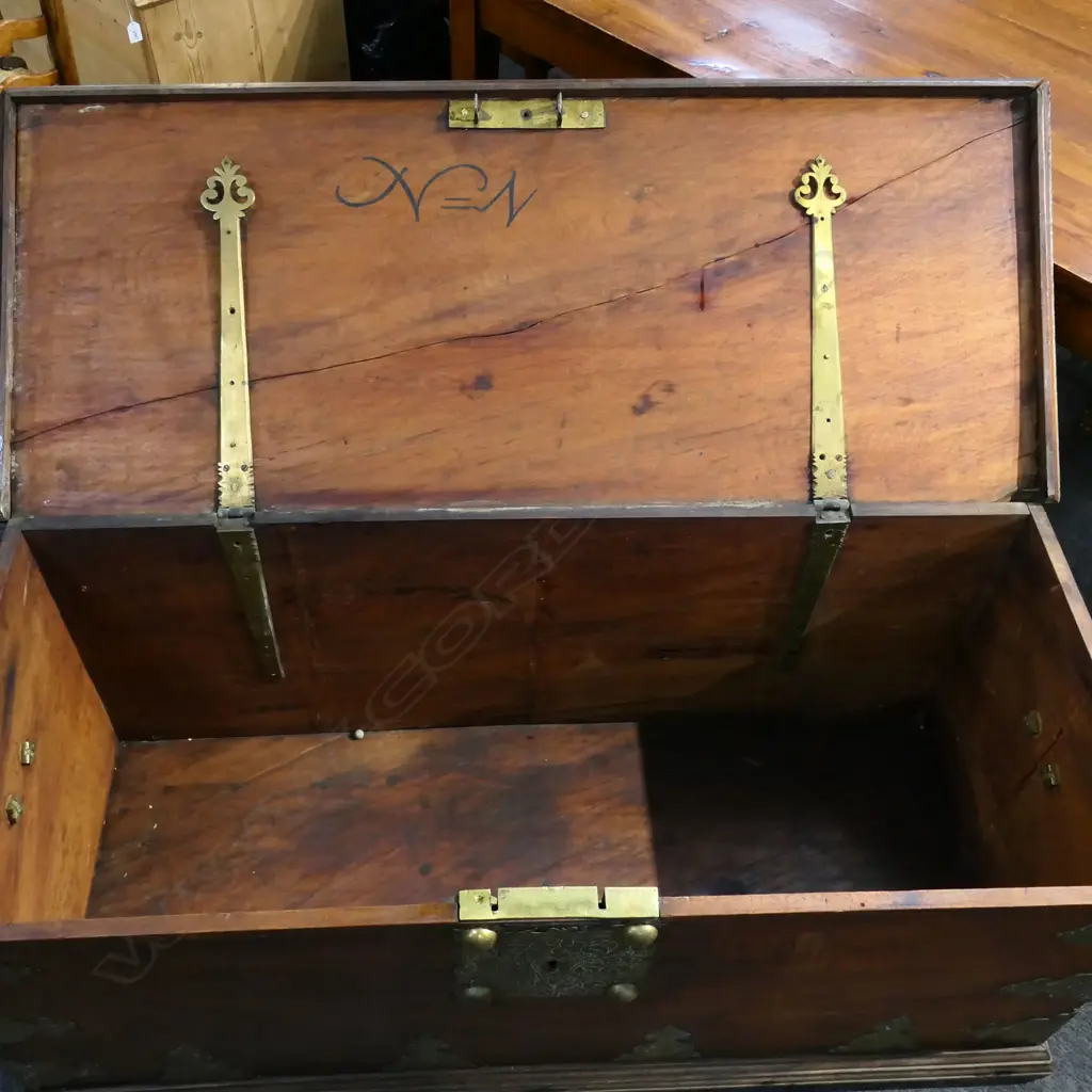 A 19thC mahogany Zanzibar large trunk - flat top, with large brass domed bosses, lock plate, engraved and fret cut brackets and side handles. The top and back with split. 1430 x 600 x 595mm. Good old patina. Image 1++