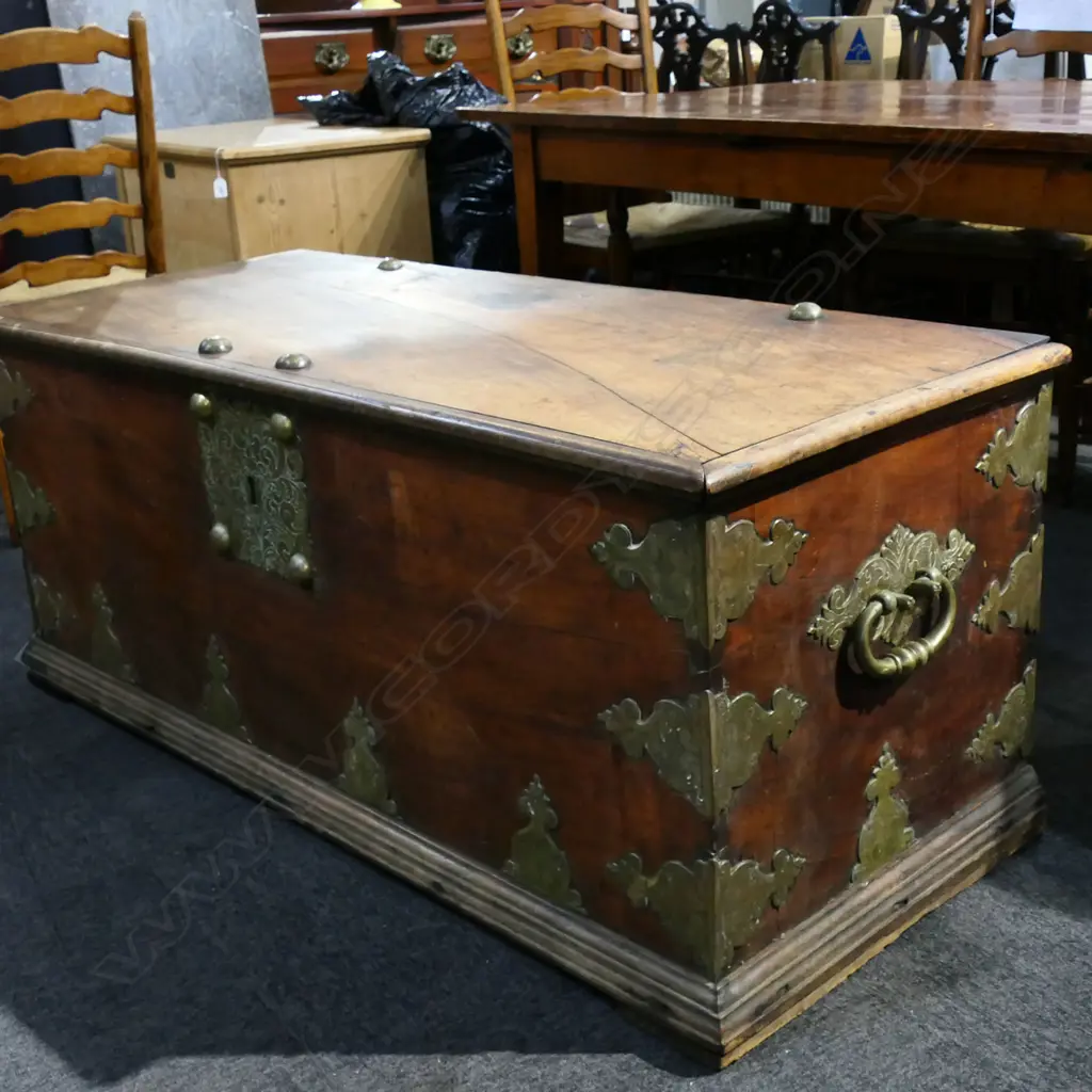 A 19thC mahogany Zanzibar large trunk - flat top, with large brass domed bosses, lock plate, engraved and fret cut brackets and side handles. The top and back with split. 1430 x 600 x 595mm. Good old patina. Image 1++