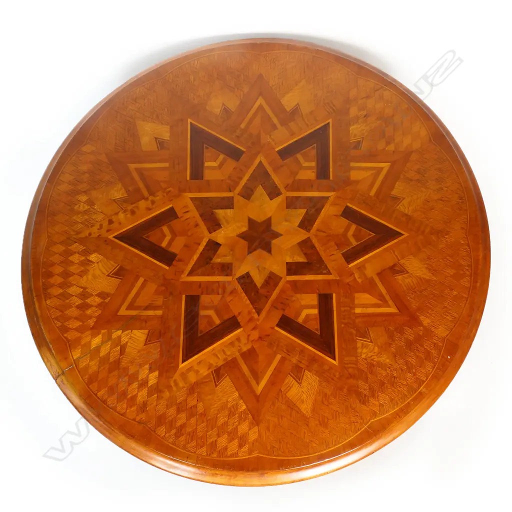 Anton Seuffert (1815-1887 New Zealand) fine and rare tilt-top specimen card table - the top with central multi-pointed starburst originating from a six-pointed star, on a fine rewarewa parquetry ground with traditional Seuffert scalloped border. The inlay of various N.Z. native timbers. On mottled Kauri tapering barley twist stem and three scroll legs. Dia.555mm. H.760mm. Image 1++