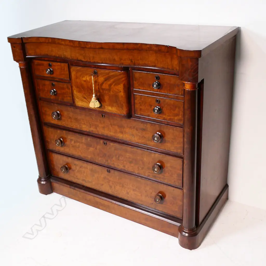 An impressive Victorian flame mahogany scotch chest - serpentine shape top, with secret frieze drawer, two hat box drawers and two half drawers over three full width drawers, pillars to each side, raised on plinth base. 1290 x 600 x 1185mm. Image 1++