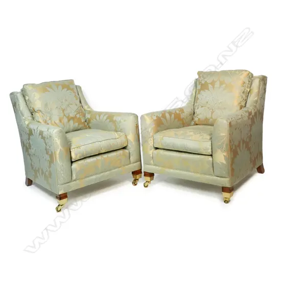 A pair of Duresta designer opera chairs - upholstered in a self-patterned fabric of muted gold and light teal, separate cushions and substantial brass casters. 700 x 900 x 900mm.