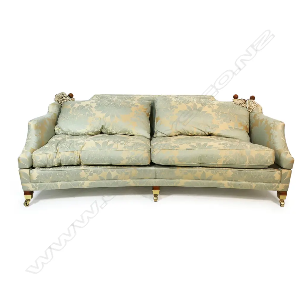 A Duresta designer three seater Knole sofa - upholstered in a self-patterned muted gold and light teal fabric, with conforming wood and cord tassels, (two faulted), with separate cushions and substantial brass casters. Provenance: Purchased from Baran de Bourdeaux Fine Antiques. This piece has been in storage for a number of years. 2300 x 1200 x 900mm. Image 1++