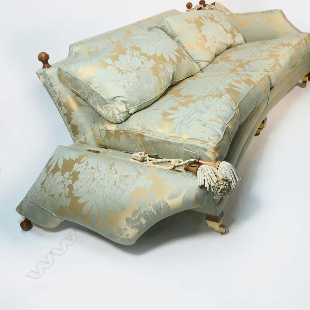 A Duresta designer three seater Knole sofa - upholstered in a self-patterned muted gold and light teal fabric, with conforming wood and cord tassels, (two faulted), with separate cushions and substantial brass casters. Provenance: Purchased from Baran de Bourdeaux Fine Antiques. This piece has been in storage for a number of years. 2300 x 1200 x 900mm. Image 1++