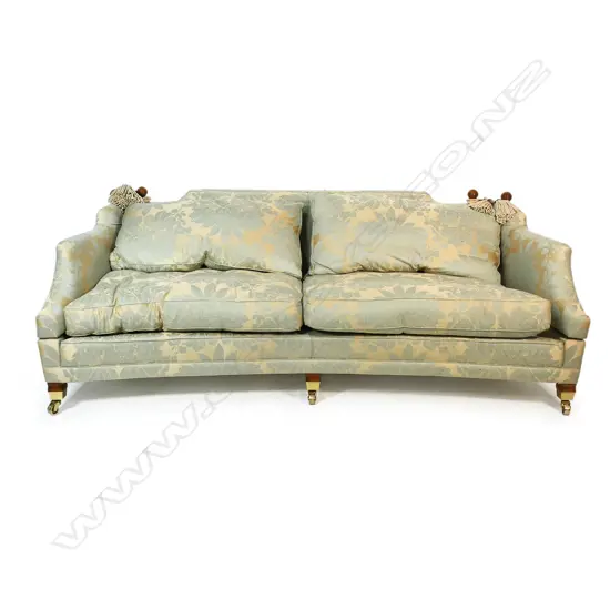 A Duresta designer three seater Knole sofa - upholstered in a self-patterned muted gold and light teal fabric, with conforming wood and cord tassels, (two faulted), with separate cushions and substantial brass casters. Provenance: Purchased from Baran de Bourdeaux Fine Antiques. This piece has been in storage for a number of years. 2300 x 1200 x 900mm.