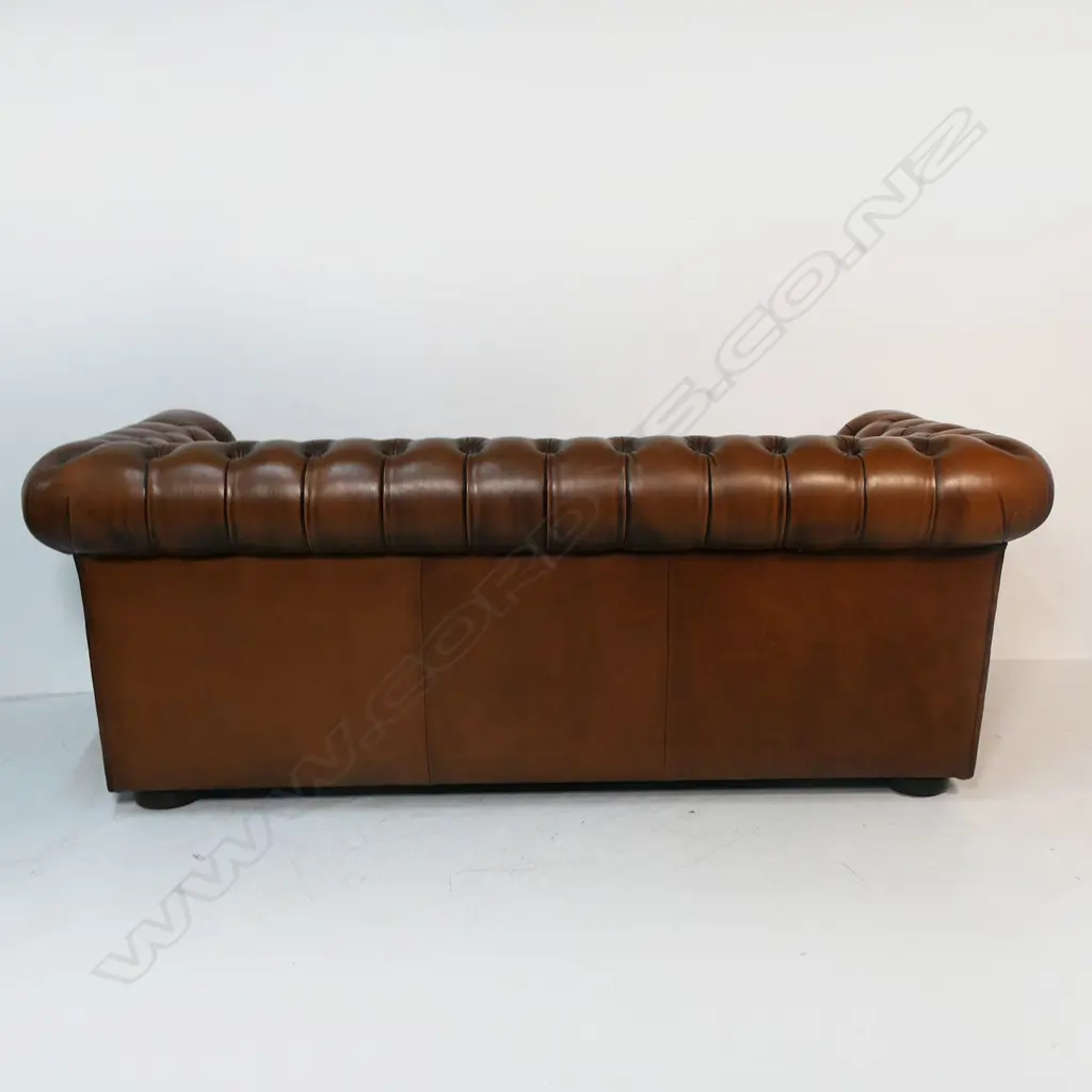 A brown buttoned leather roll arm two-seater chesterfield sofa - by Moran of Australia, of 'full grain bovine leather', buttoned to the back, arms and front with large tarnished copper studded detail. Minor wear. L.1900. H.710mm. Image 1++