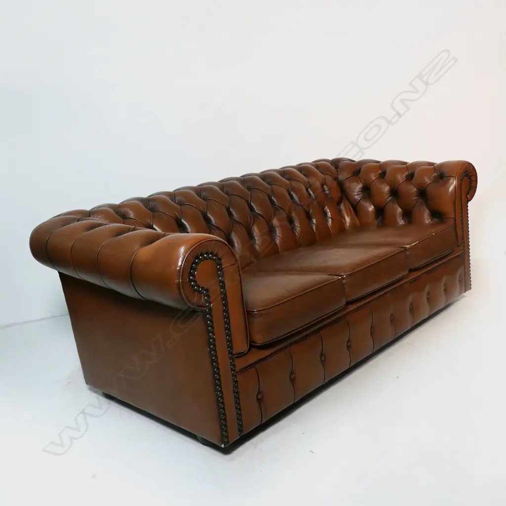 A brown buttoned leather roll arm two-seater chesterfield sofa - by Moran of Australia, of 'full grain bovine leather', buttoned to the back, arms and front with large tarnished copper studded detail. Minor wear. L.1900. H.710mm. Image 1++