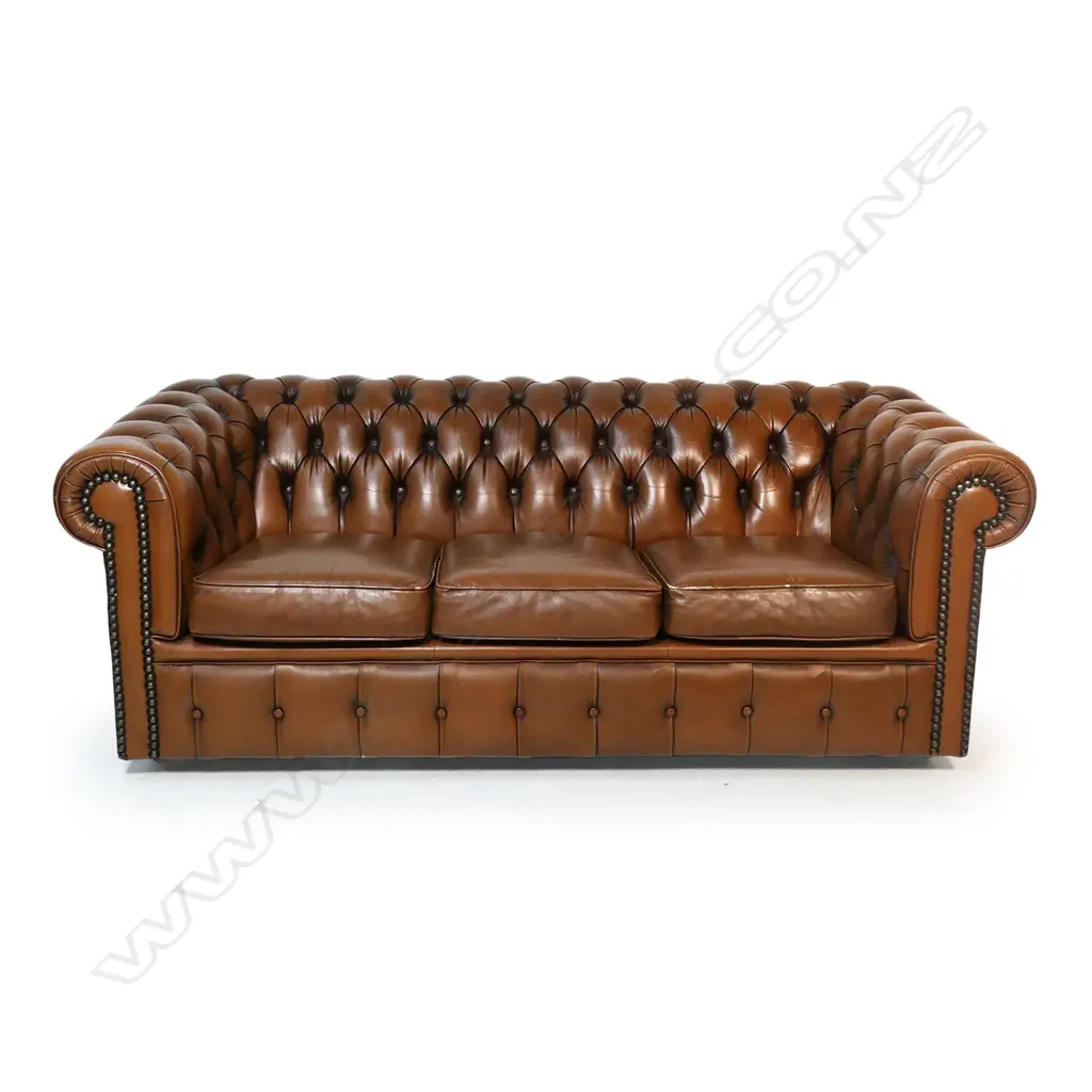 A brown buttoned leather roll arm two-seater chesterfield sofa - by Moran of Australia, of 'full grain bovine leather', buttoned to the back, arms and front with large tarnished copper studded detail. Minor wear. L.1900. H.710mm. Image 1++
