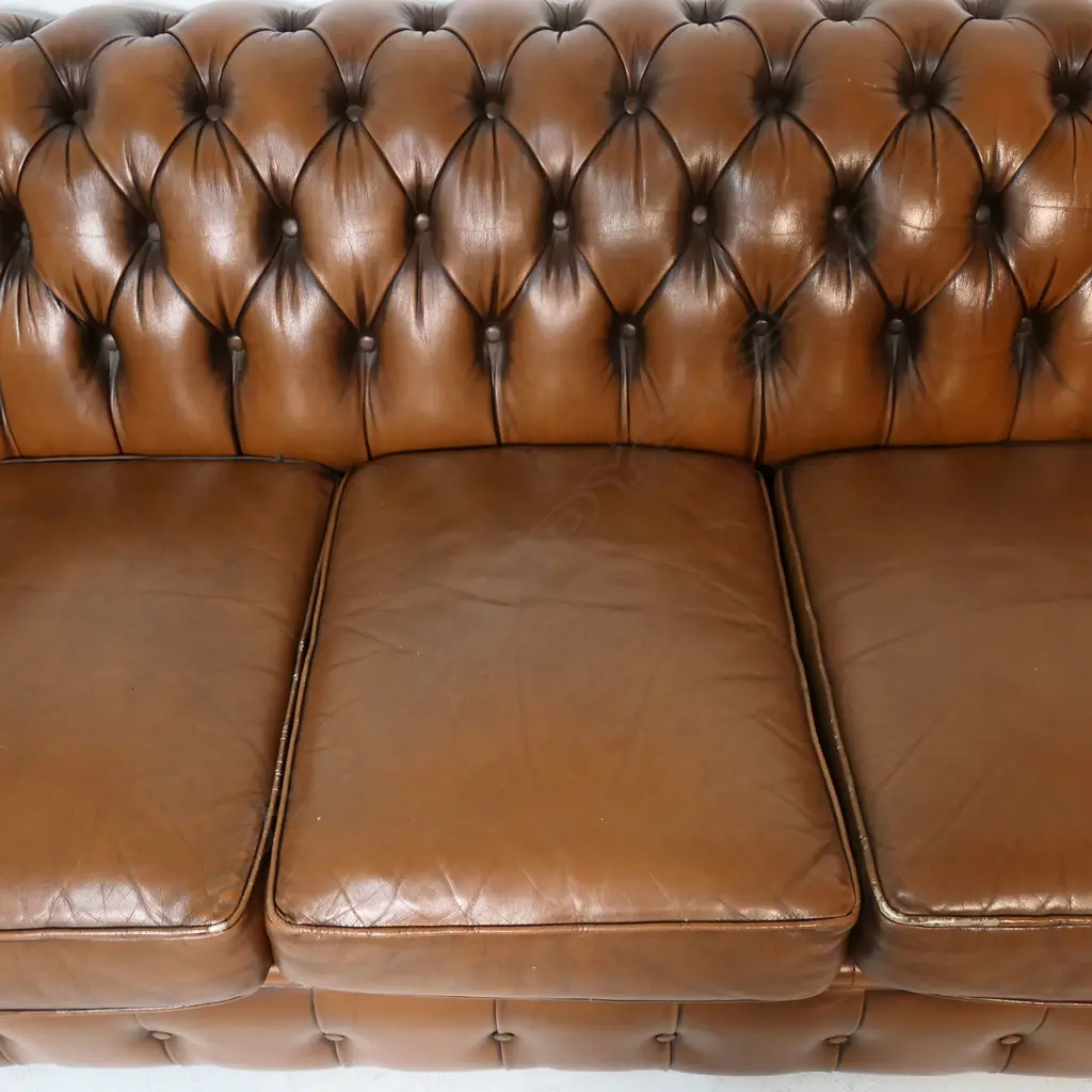A brown buttoned leather roll arm two-seater chesterfield sofa - by Moran of Australia, of 'full grain bovine leather', buttoned to the back, arms and front with large tarnished copper studded detail. Minor wear. L.1900. H.710mm. Image 1++