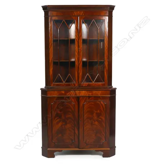 An antique style mahogany corner cabinet - the astragal glazed top with two doors, decorative pediment, over the base with two panelled doors with figured mahogany, raised on bracket feet. 900 x 400 x 1780mm.