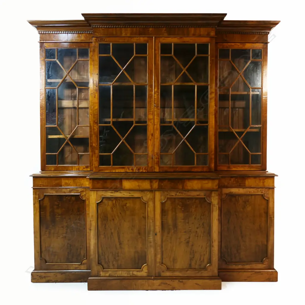 A mahogany Georgian style breakfront bookcase - dentil moulding to the pediment, four astragal glazed doors, the interior with two adjustable shelves, the base with four panelled doors, raised on plinth base. 1920 x 490 x 2000mm. Made by Don Barrett, cabinet maker and antique furniture restorer, for his family home. Image 1++