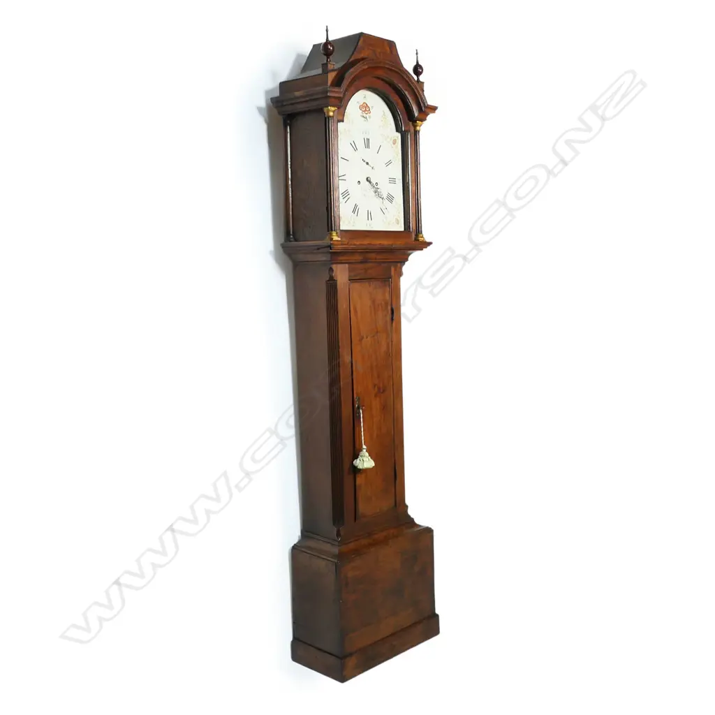 A Georgian oak long case clock - the hood with two finials, (one absent), reeded column with brass detail to each side, the dial with painted floral decoration, Roman numerals with the minutes in Arabic numerals, seconds dial, marked Edwd. Maud, Daventry, chamfered sides to case. 460 x 240 x 2600mm. Image 1++