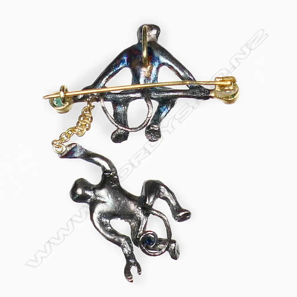 An antique style silver gilt monkey brooch a monkey sits on a branch with another hanging by a gold chain. Both monkeys embellished with rose cut diamonds, red spinel eyes and cabochon emeralds to each end of the branch. TDW. 0.50ct. TEW. 0.30ct. 3.76gms. (one diamond missing on hanging monkey). Image 1++