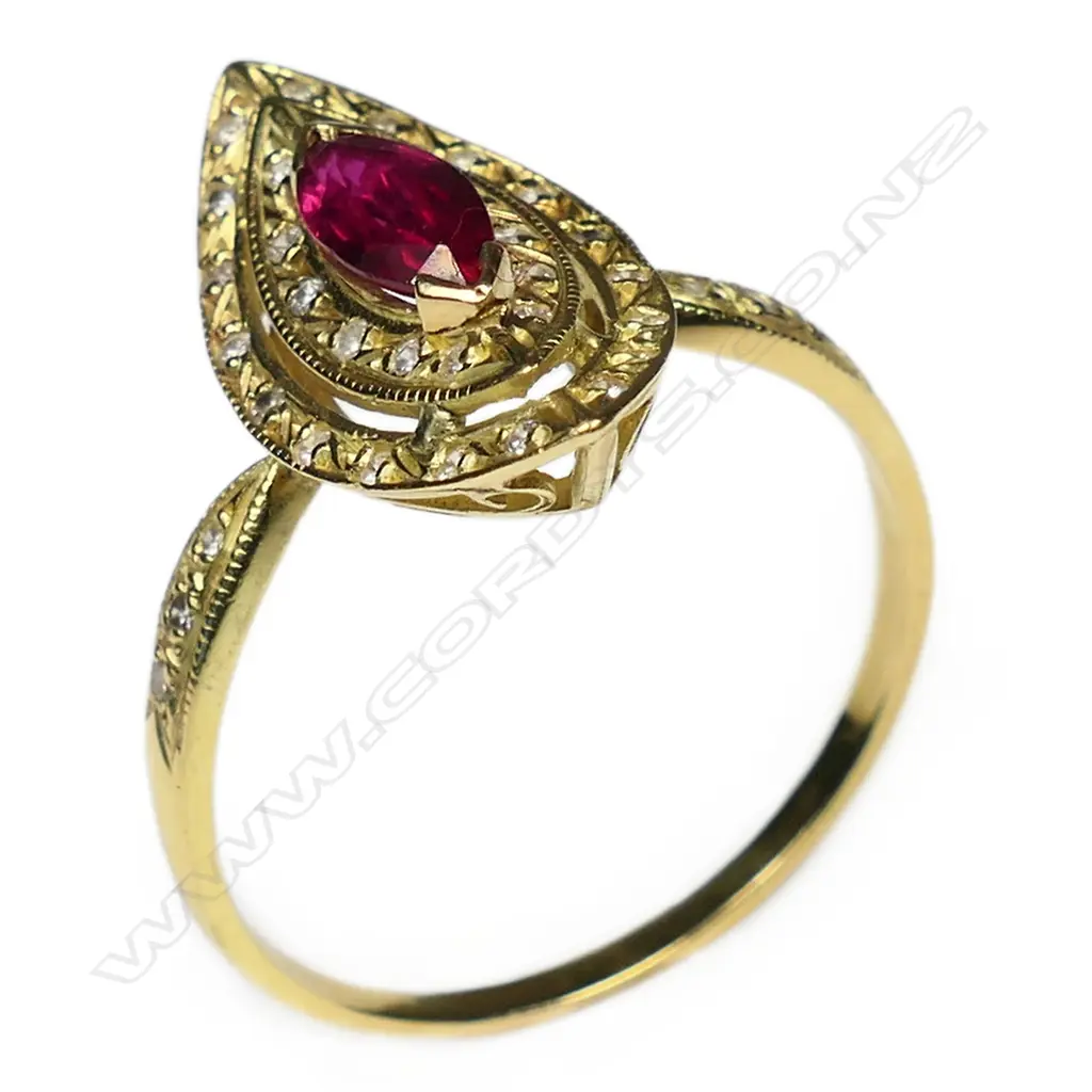 A 18ct gold ruby and diamond ring the marquis cut bright red ruby bar set at each end and surrounded by two curved marquis shaped diamond set halos three single cut diamonds to each shoulder. Image 1++