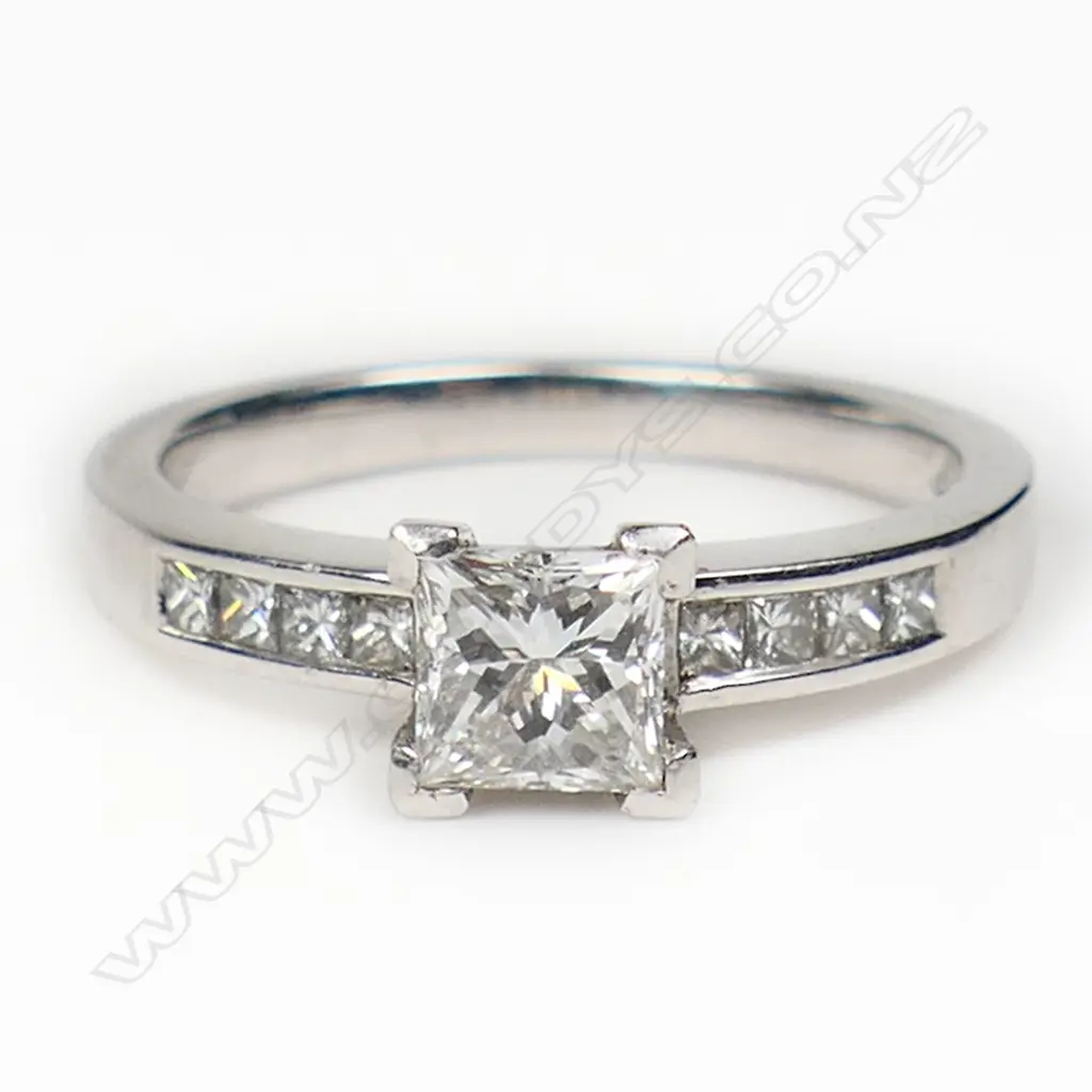 A platinum and diamond ring with a 0.50ct princess cut diamond channel set, with a further four small princess cut diamonds set to each shoulder. TDW. 0.80ct. Size M. Image 1++