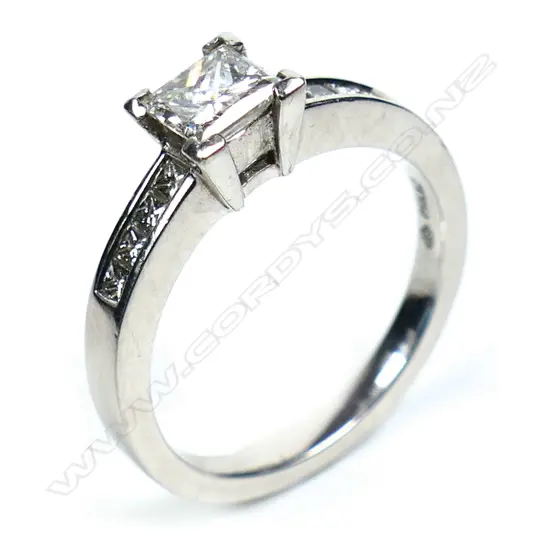 A platinum and diamond ring with a 0.50ct princess cut diamond channel set, with a further four small princess cut diamonds set to each shoulder. TDW. 0.80ct. Size M.