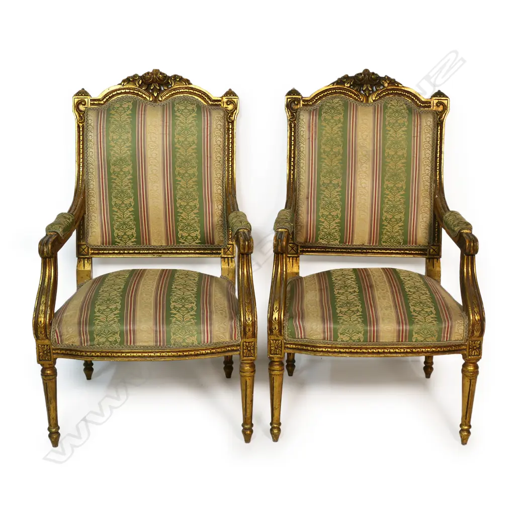 A pair of French style open elbow armchairs the gilded frames with carved decoration upholstered in a stripped patterned fabric. The back of both chairs require reupholstering. 570x 570 x 1050mm. Image 1++