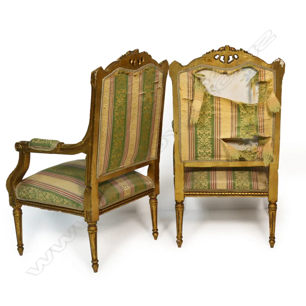A pair of French style open elbow armchairs the gilded frames with carved decoration upholstered in a stripped patterned fabric. The back of both chairs require reupholstering. 570x 570 x 1050mm. Image 1++