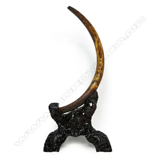 An ancient full woolly mammoth tusk on carved stand,
