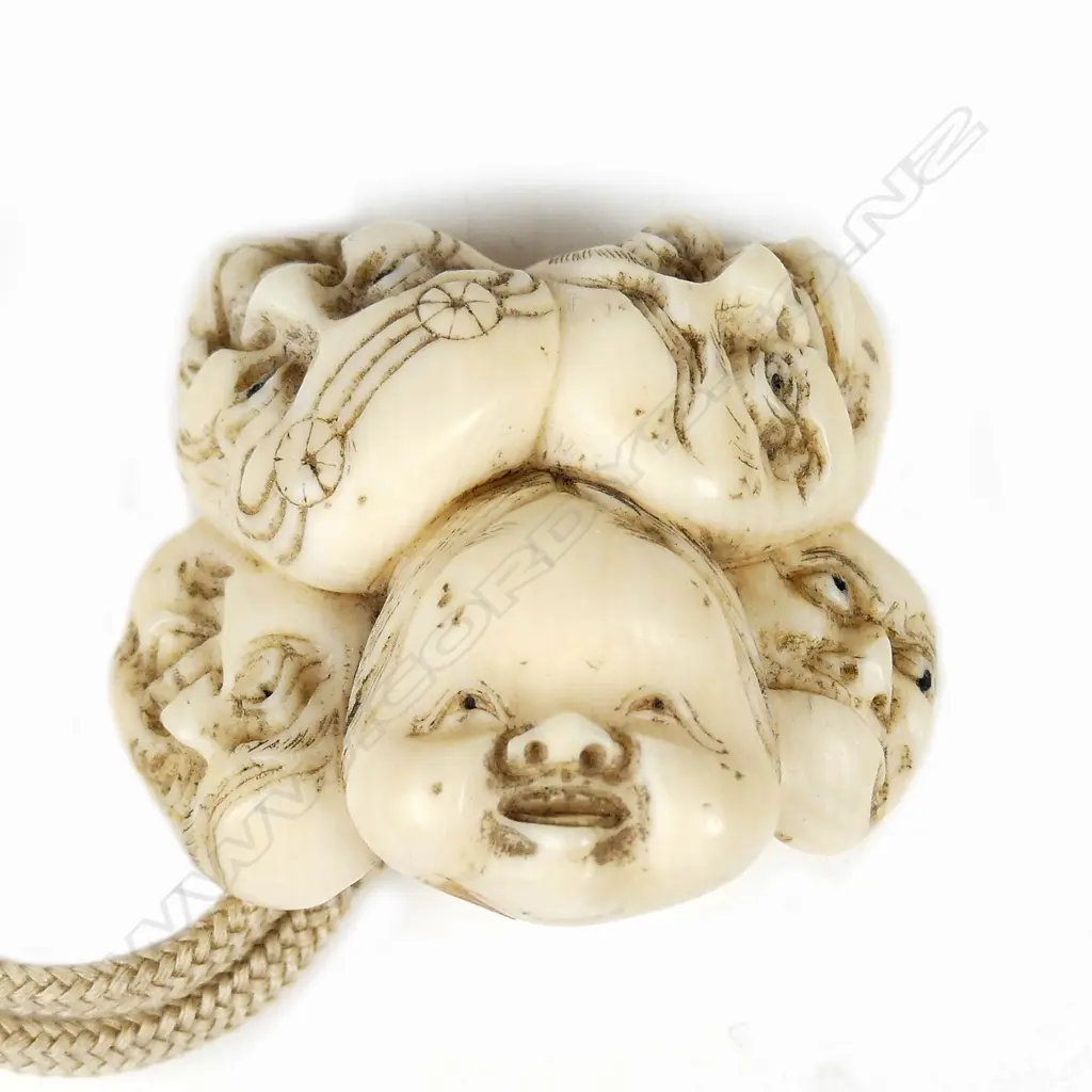 A Japanese ivory netsuke of a group of five masks including Okame Image 1++