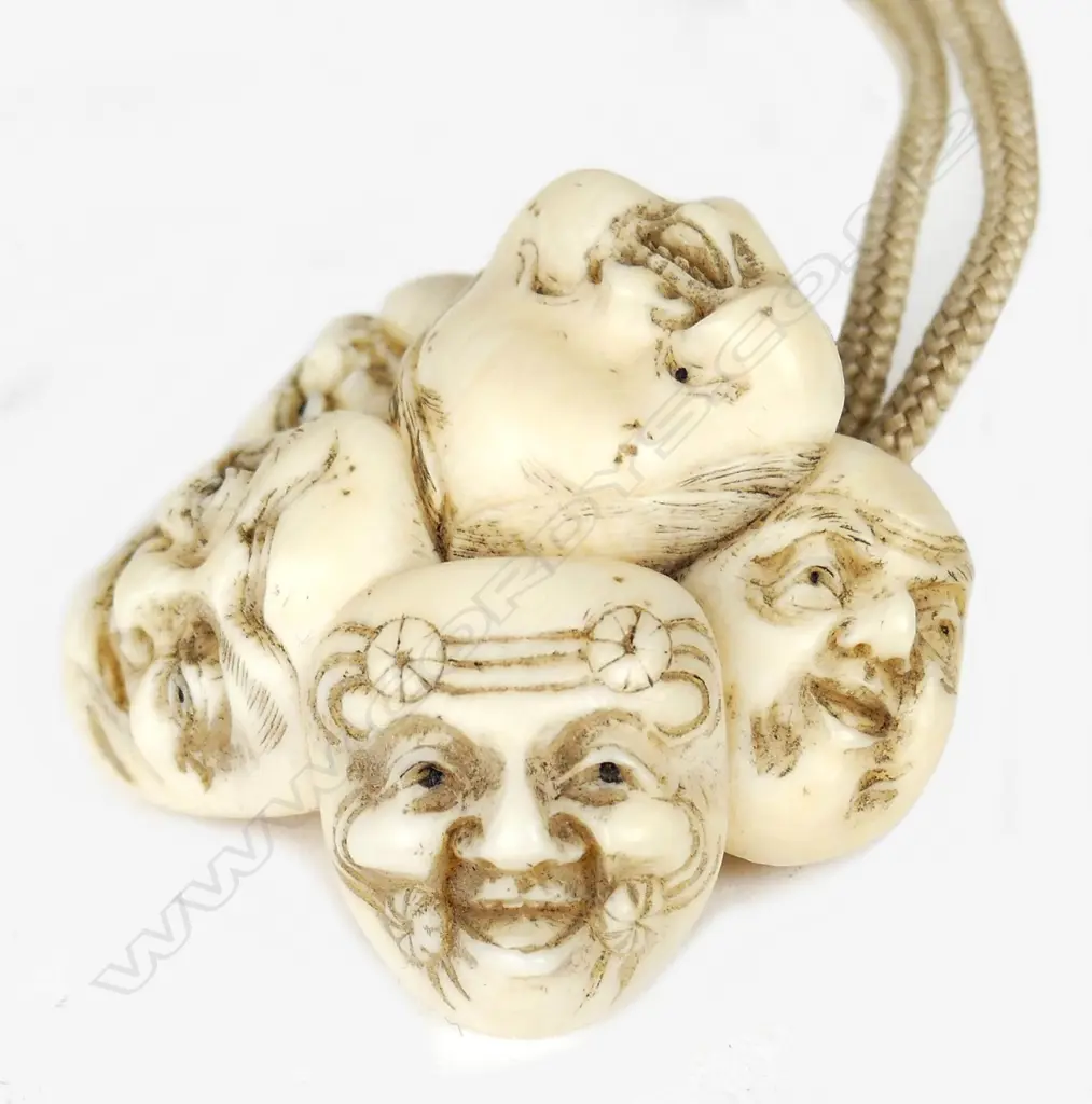 A Japanese ivory netsuke of a group of five masks including Okame Image 1++