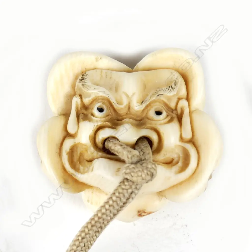 A Japanese ivory netsuke of a group of five masks including Okame Image 1++