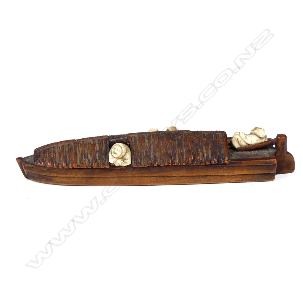 A Japanese boxwood and ivory netsuke of a figures relaxing on a sampan Image 1++