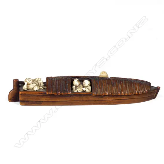 A Japanese boxwood and ivory netsuke of a figures relaxing on a sampan