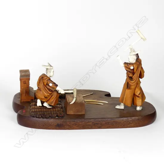 A Japanese Meiji period boxwood and ivory okimono of two swordsmiths