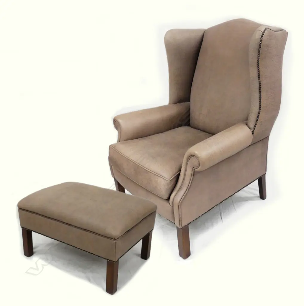 A contemporary leather wingback armchair and matching oblong ottoman Image 1++