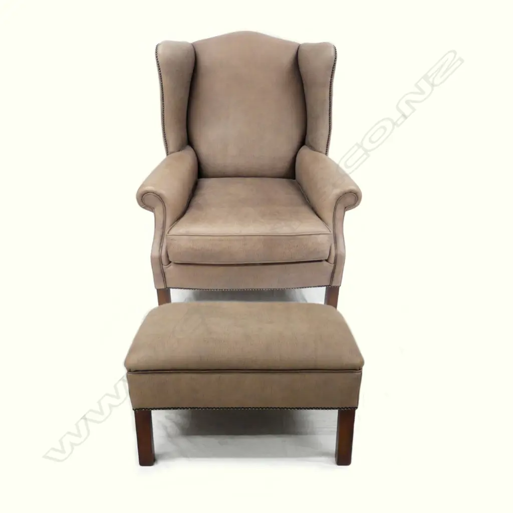 A contemporary leather wingback armchair and matching oblong ottoman Image 1++