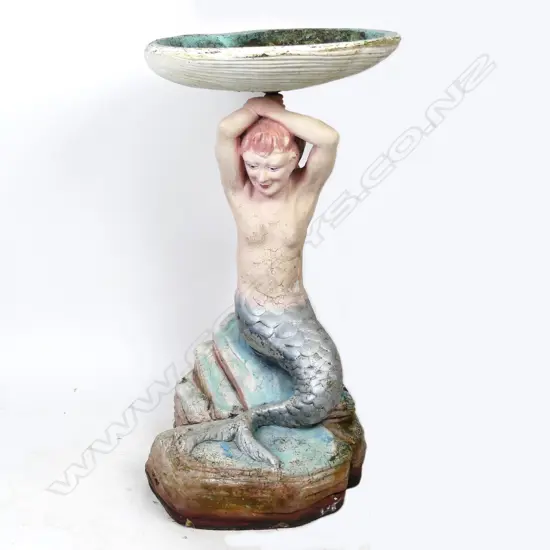A vintage concrete mermaid birdbath